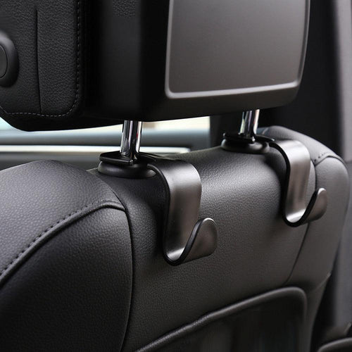 Car headrest hook attached to a car's headrest with a phone and bag on it.